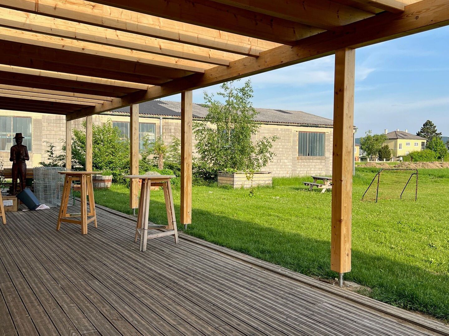 Überdachte Terrasse mit Blick ins Grüne und Holzstehtischen